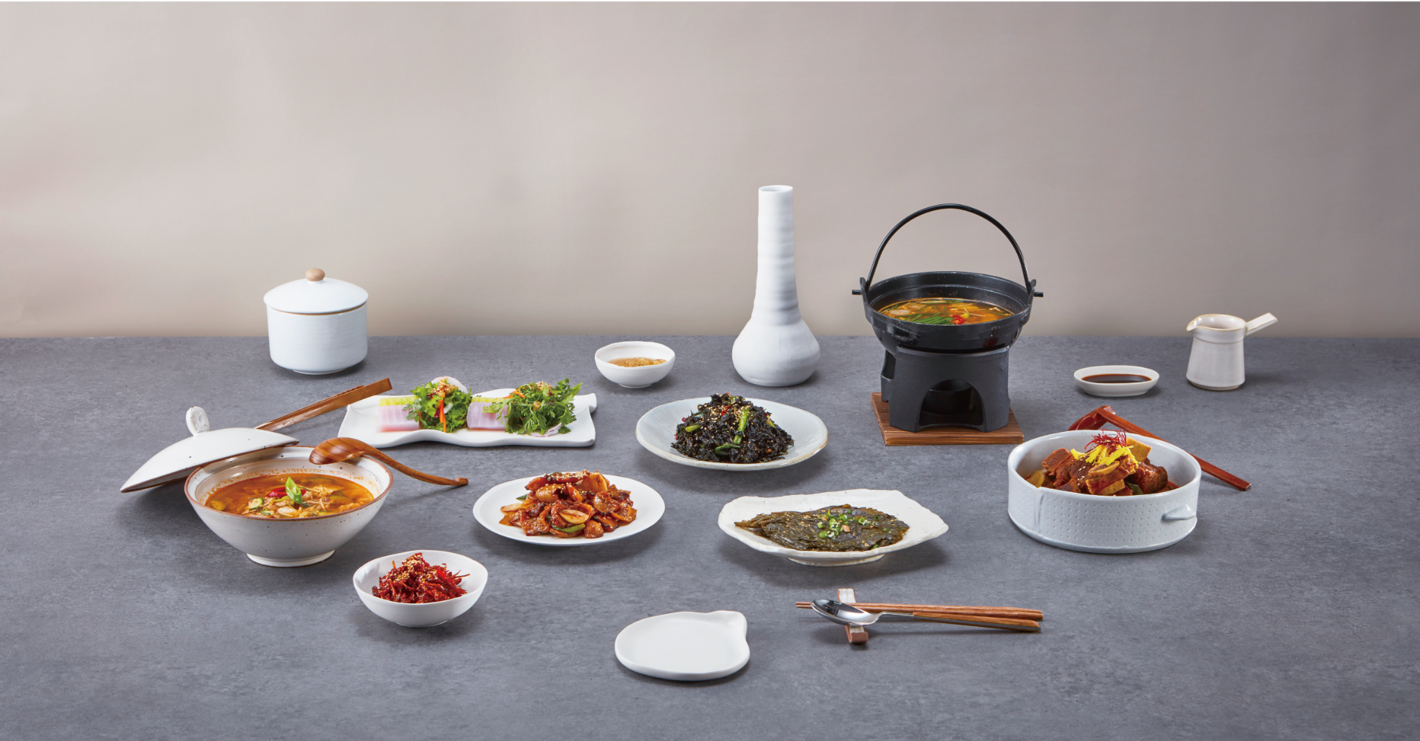 A thoughtfully arranged Korean table with side dishes, soup and white ceramic serving dishes